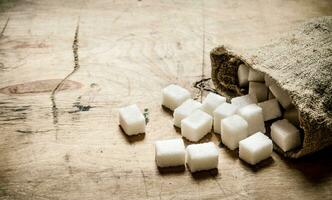 blanco refinado azúcar en el bolsa. en de madera antecedentes. foto