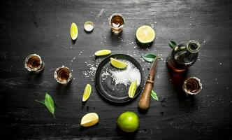 bottle of tequila with shot glasses, fresh lime and salt. photo