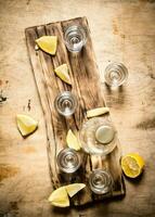 Bottle of vodka with shot glasses and lemon. photo