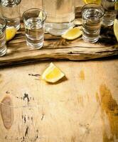 Bottle of vodka with shot glasses and lemon. photo