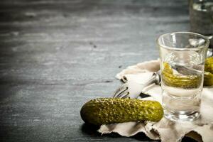 Glasses with vodka and pickled cucumbers on the old fabric. photo