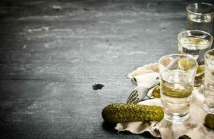 Glasses with vodka and pickled cucumbers on the old fabric. photo