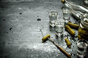 Russian style. Bottle vodka with shot glasses and pickled cucumbers . photo