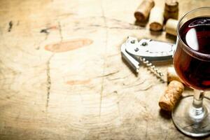 glass of red wine with corks and a corkscrew. photo