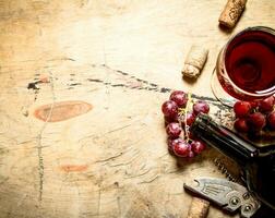 Red wine with grapes and corks. photo