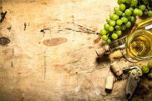 Bunch of white grapes with wine, a corkscrew and stoppers. photo