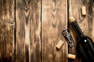 Bottle of red wine with a corkscrew and corks. photo