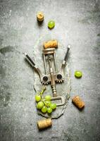 Wine corkscrew with grapes and corks. photo