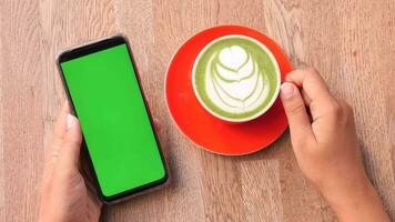 tenendo una cpu di caffè e utilizzando uno smartphone con schermo verde video