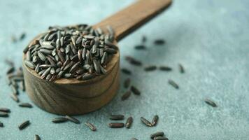 Black Rice Grains in a wooden spoon on black background video