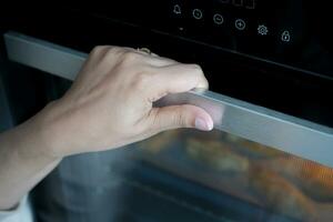 women hand open electric oven at home photo