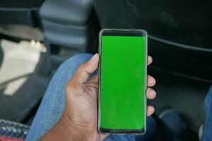 hand holding smart phone with empty screen in a car photo