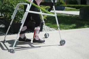 child with walking frame and knee orthosis outdoor photo