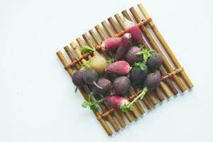 Fresh red and black radish bundle on chopping board on table photo