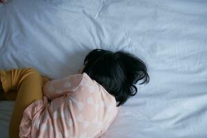 a upset child girl in a white bad hiding her face photo