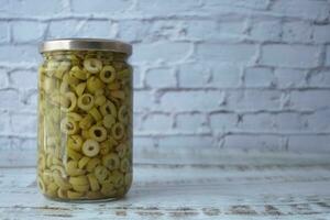 sliced green olives in a glass jar photo