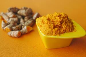 turmeric root and paste in a bowl on white background photo
