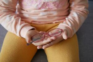 child holding a eyeglass sitting on sofa photo