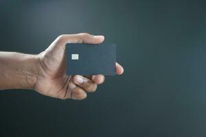 close up of person hand holding credit card against black background photo