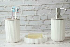 colorful toothbrushes in white mug soap and hand sanitizer on desk photo