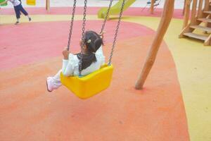 child having fun on a swing on the playground in public park. photo