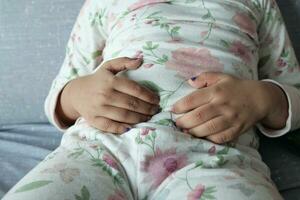 child suffering stomach pain sitting on sofa photo