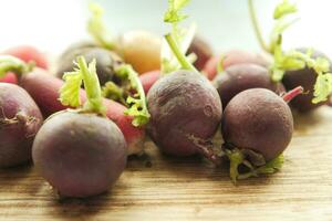 Fresh red radish bundle on chopping board on table photo