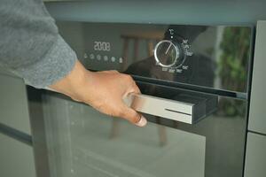 person hand open electric oven at home photo