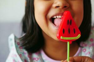 child is licking colorful candy on stick, photo