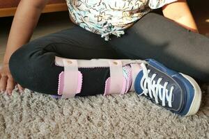 child with legs orthosis shoes sitting on carpet at home photo