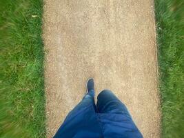 POV shot of man in shoe walking on road photo