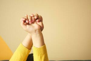 children with their hands up against yellow background photo