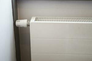 White radiator on grey white wall. apartment heating installation system, photo