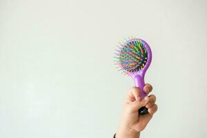 child hand holding a colorful hair brush at home , photo