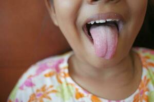 child shows his tongue closeup photo