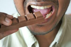 young man eating dark chocolate close up photo