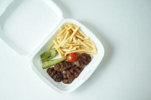 kebab meat with french fries in a packing box , photo