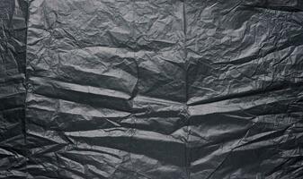 Crumpled sheet of black parchment paper, abstract background photo