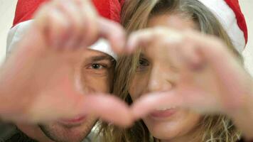 marrant couple dans Père Noël chapeau furtivement par le cœur de le les doigts video