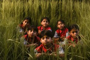 Young children in red scarfs posing for a picture in a field photo