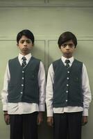 Two Boys in School Uniforms Posing in Front of a Green Wall photo