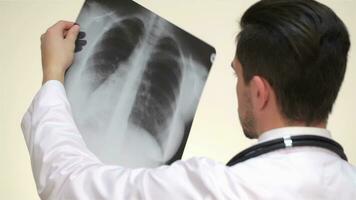médico examina un radiografía ver desde el espalda video