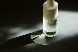 Cosmetic or medical glass bottle with pipette. Skin care concept. Natural hard light, deep shadows. - Image photo