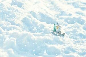 Snowman in a sleigh with a Christmas tree in snowdrifts. Winter season background. photo