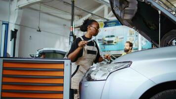 gecertificeerd technicus in reparatie winkel gebruik makend van koppel moersleutel naar vastdraaien schroeven na controle auto parameters gedurende onderhoud. Afrikaanse Amerikaans deskundige gebruik makend van professioneel gereedschap in garage naar herstellen voertuig video