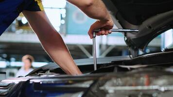 Close up shot on torque wrench used by certified mechanic in car service to tighten bolts after fixing vehicle parts. Repairman utilizing professional tools to repair automobile video