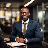 Dark-skinned African-American man smiling, a businessman in an office at a desk with a laptop.Generative AI photo