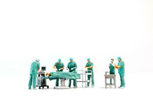 miniatura médico ejecutando cirugía en paciente en blanco antecedentes foto