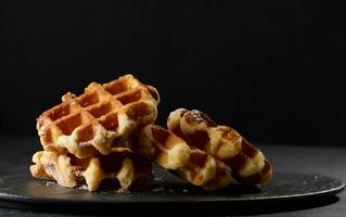 A stack of baked Belgian waffles sprinkled with powdered sugar photo