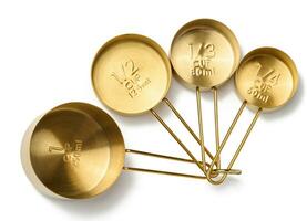 Golden metal measuring spoons for bulk and liquid products on a white isolated background, top view photo